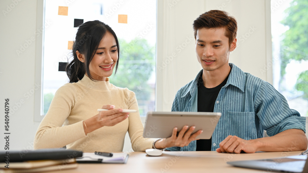 Two young Asian female and male marketing workers discussing on their project. Two young Asian female and male marketing workers discussing on their project.