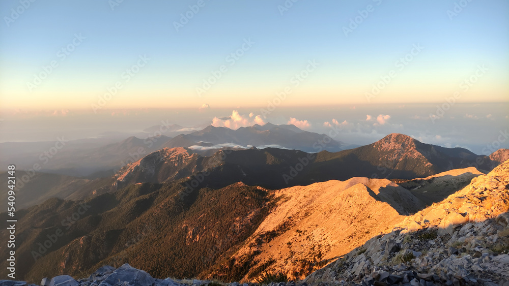 sunset over the mountains , above the clouds with sunny beams. Profitis ilias mountain in greece