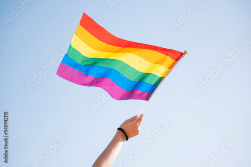 Hand of a woman waving an LGBT pride flag.