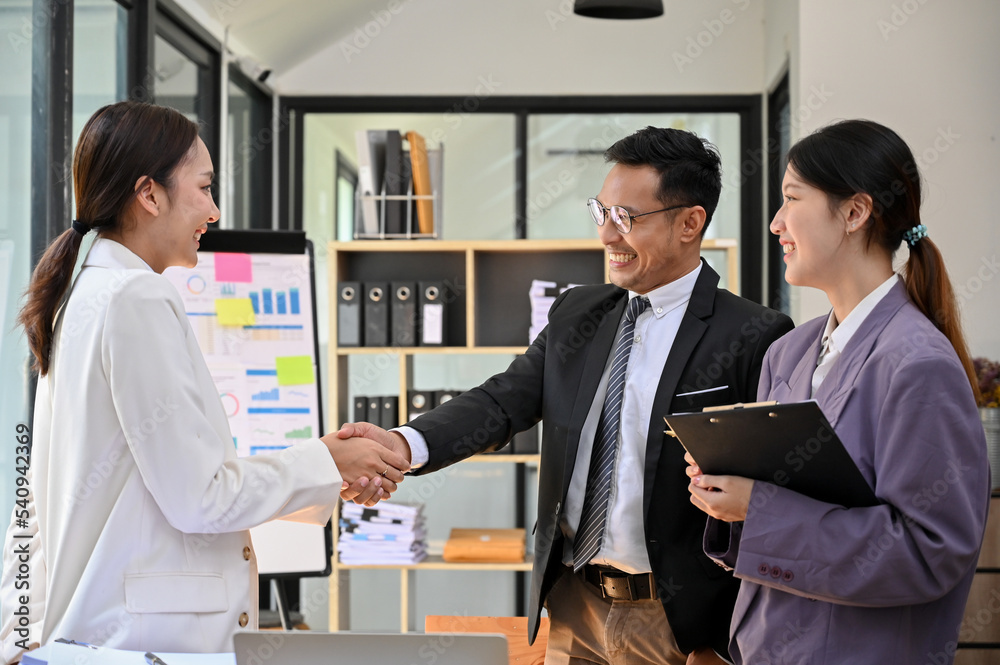 Professional adult Asian businessman shaking hand with a female business partner Professional adult Asian businessman shaking hand with a female business partner