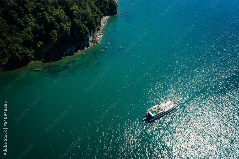 Aerial view of a sailboat anchored off a rocky coast