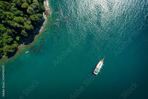 Obraz na płótnie Top view of a sailboat anchored off a rocky coast w salonie