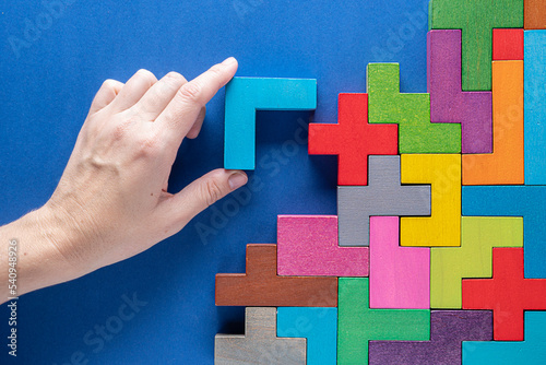 Concept of decision making process. Logical tasks. Hand holding wooden puzzle element. Hand sets the element of the puzzle.