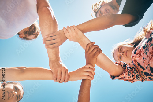 Support, holding wrists and friends in a circle for collaboration, trust and teamwork outdoors. Diversity, love and people in a community with compassion, respect and unity with a sky blue background