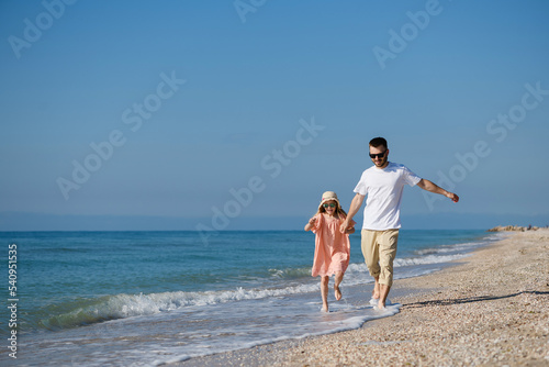 Father and girl running at sea coast