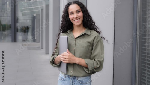 Smiling Latina Caucasian Hispanic 30s woman with laptop businesswoman teacher HR manager recruiter outdoors in city welcome invite wave hand come on go here welcoming motivated to join invitation photo