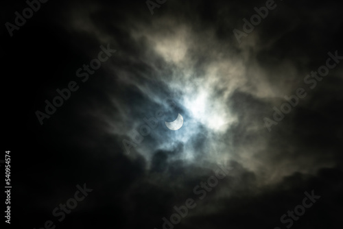 Partial solar eclipse behind clouds. The moon partially covers the sun. Natural, rare phenomenon seen 25 October 2022. 