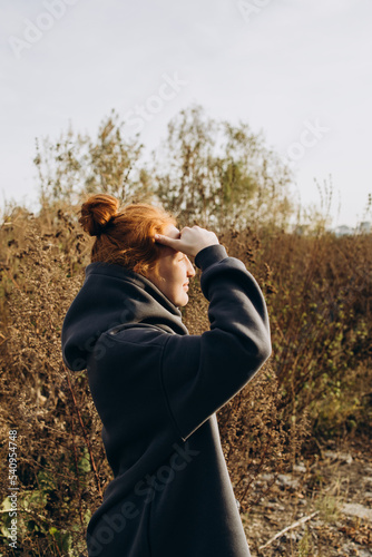 Red-haired girl looks at the setting sun