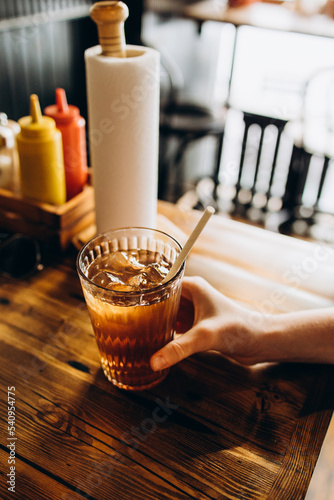 Glass of lemonade in hand on bar table