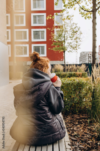 Red-haired girl drinking coffee on the street