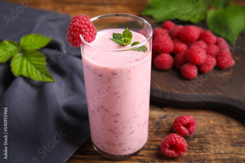Glass of tasty fresh raspberry smoothie on wooden table