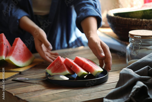 Woman taking plate with slices of fresh watermelon, closeup