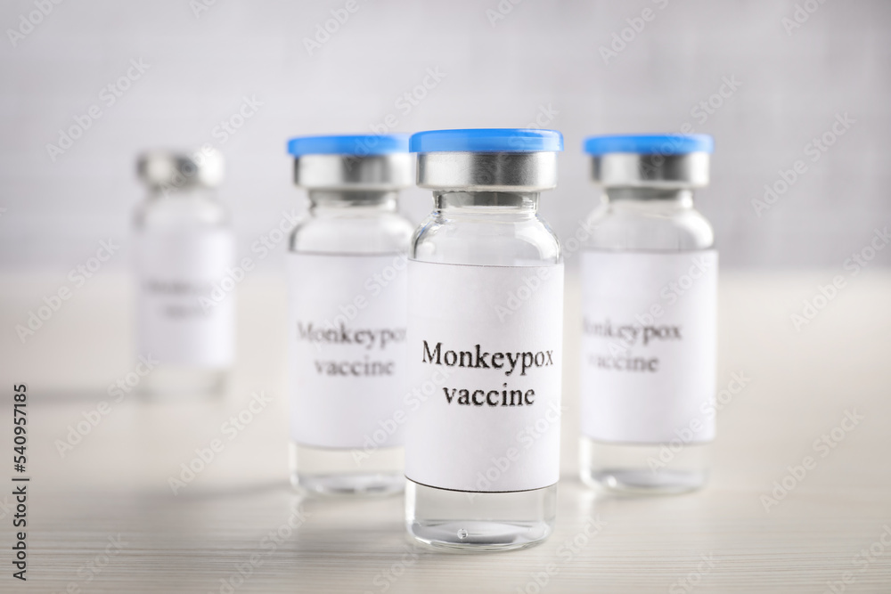 Monkeypox vaccine in glass vials on white wooden table Monkeypox vaccine in glass vials on white wooden table