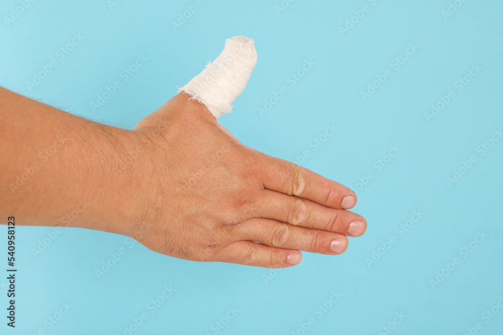 Man with thumb wrapped in medical bandage on light blue background, closeup Man with thumb wrapped in medical bandage on light blue background, closeup