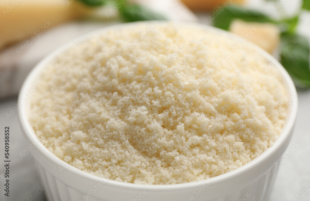 Bowl with grated parmesan cheese on light table, closeup Bowl with grated parmesan cheese on light table, closeup