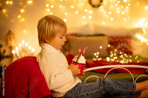 Cute child, boy, sitting on a yellow armchair in a decorated room for Christmas