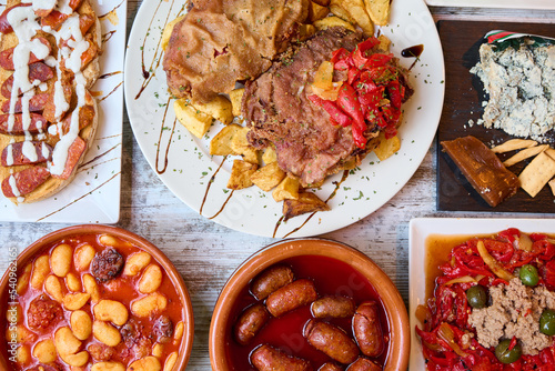 table with typical Asturian food, Asturian cachopo, Asturian bean stew, Cabrales cheese and sausage in cider photo