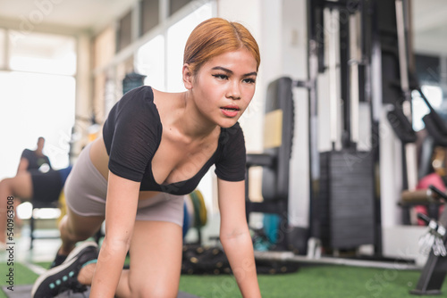 A young asian woman does a set of slow mountain climbers while at the gym. Challenging herself to train a high number of repetitions.