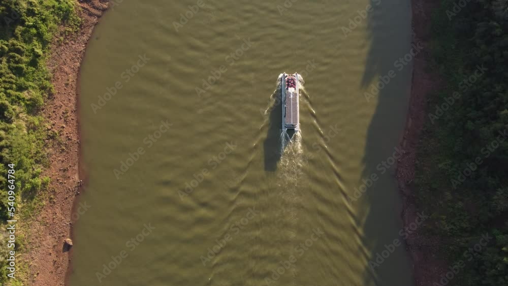 Tourist boat along Iguazu river at dusk, border between Argentina and Brazil. Aerial top-down forward directly above Tourist boat along Iguazu river at dusk, border between Argentina and Brazil. Aerial top-down forward directly above