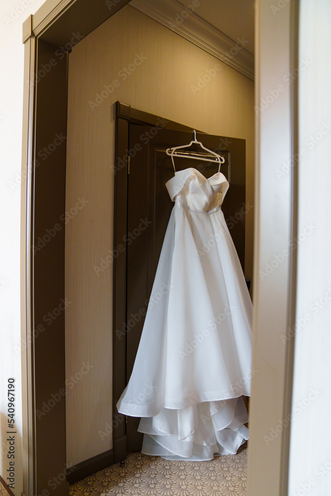 Classic simple white wedding dress on the door.