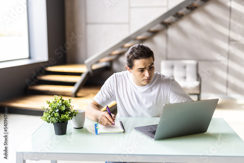 Successful man smiling in satisfaction as he checks information on his laptop computer while working