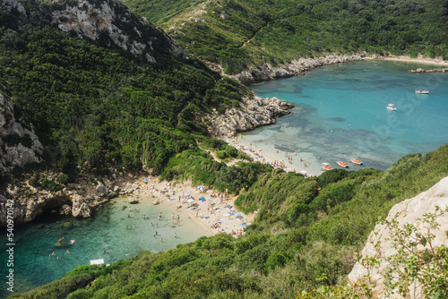 Porto Timoni beach. Vacation in Greece background. Corfu island landscape. Sunny summer paradise background. Sea shore scenic view. People on a beach enjoying vacation.