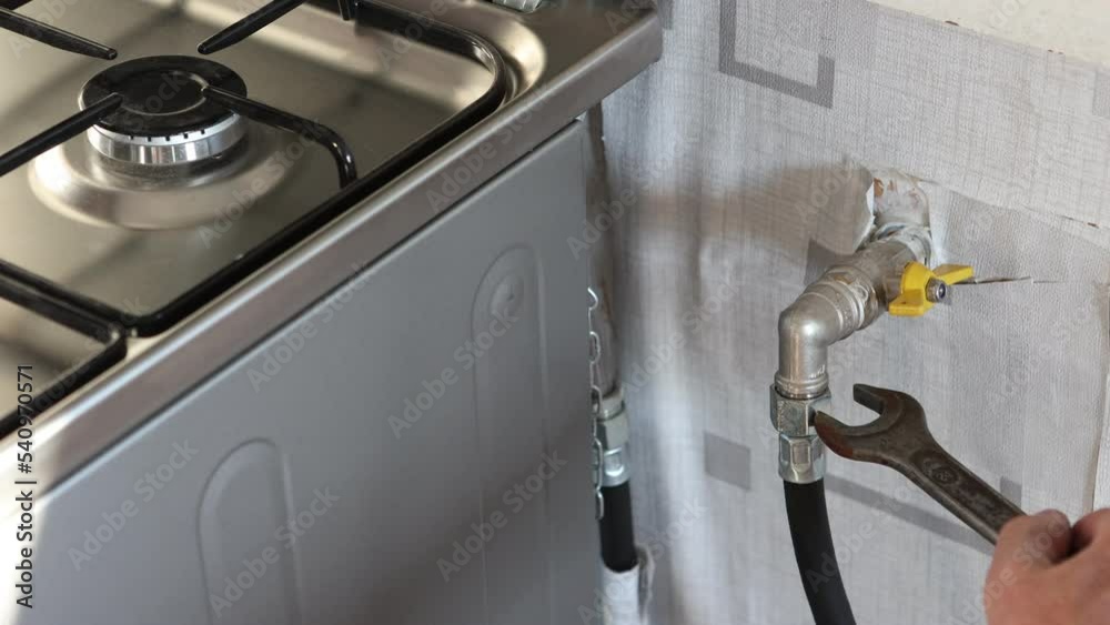 Gasman shut on gas valve and unscrewing flexible gas line onto stove with wrench.