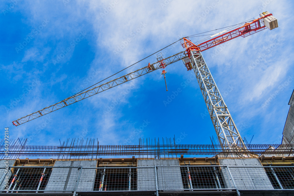 One construction crane for the construction of high-rise buildings and offices against the blue sky close-up, construction concept, bottom view One construction crane for the construction of high-rise buildings and offices against the blue sky close-up, construction concept, bottom view