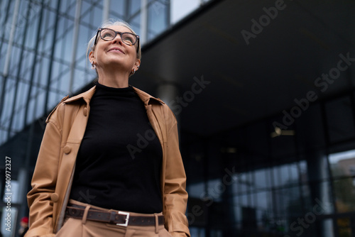 portrait of a successful mature adult charismatic female leader against the backdrop of a glass facade of an office building, business economic consultant concept