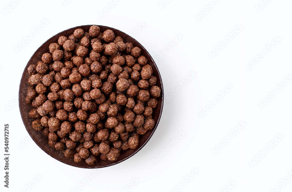 Chocolate corn flakes in a bowl on a white isolated background. Flakes with chocolate flavor, close-up top view. American-style energy carbohydrate breakfast. Free space for text Chocolate corn flakes in a bowl on a white isolated background. Flakes with chocolate flavor, close-up top view. American-style energy carbohydrate breakfast. Free space for text