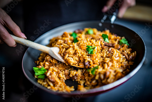 cooking tasty rice, meat and vegetable in pan on kitchen