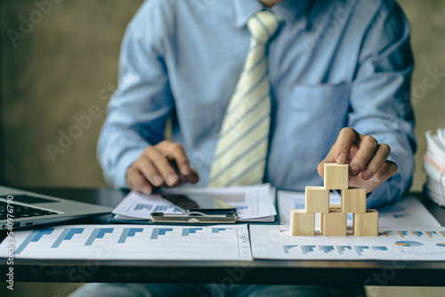 businessman laying empty wooden blocks business management concept planning and strategy Setting and achieving goals with financial graphs on the table Risk assessment. investment