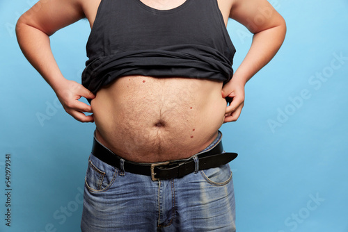 Cropped image of overweight man showing his belly, abdomen. Close up part of man's body. Concept of dieting, sport, fitness, healthy lifestyle, body positive