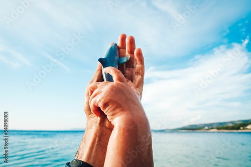 Closeup shot of hands holding a shark figurine against a seascape and cloudy sky