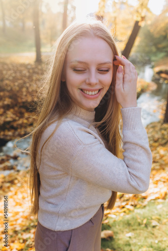 Close up blondie woman outdoor portrait in autumn park. Happy caucasian girl with long natural blondie hair 