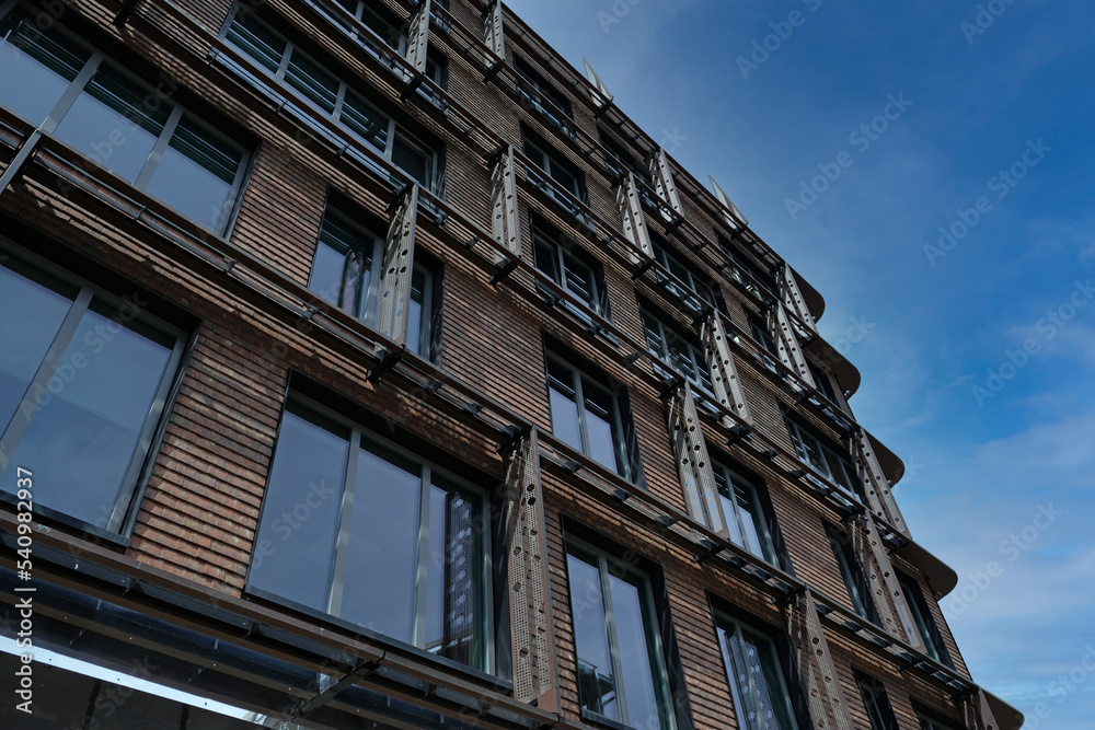 Exterior of modern red brick house with metal inserts. Architectural detail of close-up on windows. Real estate, residential apartments and offices. Living apartments or office building architecture.