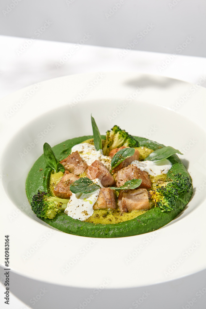 Creative dish from roasted chicken and broccoli puree on white plate. Sliced baked chicken with vegetables and creamy espuma in summer menu. Creative dish from roasted chicken and broccoli puree on white plate. Sliced baked chicken with vegetables and creamy espuma in summer menu.