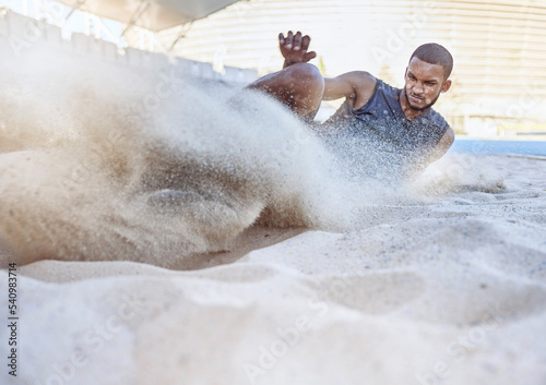 Man, athlete and sand for long jump, sport and training for sports, field and global competition. Sport, motivation and goal for podium, winning and world record for jumping at arena, stadium or park photo