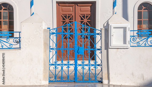 Tableau sur toile Blue iron gate at a Greek Orthodox church at Oia town on the island of Santorini