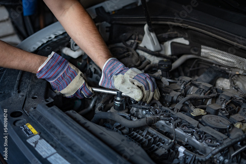 The mechanic repairs the car under the hood