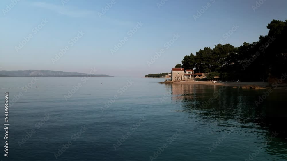 The sun rises over the small town of Brac on the island of Bol, Croatia. The town is situated on a steep hillside overlooking the Adriatic Sea. The footage is shot from the above sea, giving a bird's The sun rises over the small town of Brac on the island of Bol, Croatia. The town is situated on a steep hillside overlooking the Adriatic Sea. The footage is shot from the above sea, giving a bird's