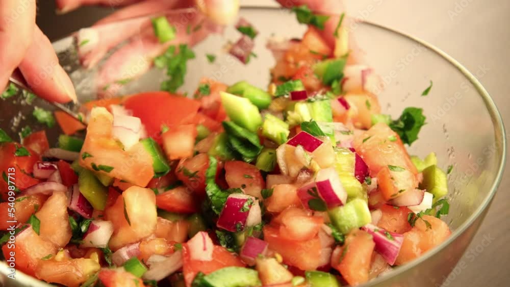 mixing tomatoes  salsa in glass bowl close up