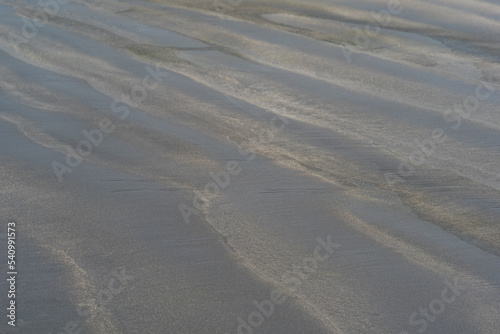 black volcanic sand beach with wave patterns