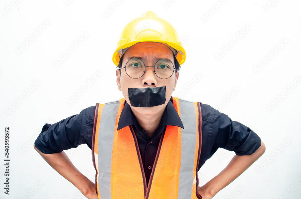 Young asian construction worker doing protest by covering mouth with tape isolated over white background. labour day concept. freeedom of speech concept. Young asian construction worker doing protest by covering mouth with tape isolated over white background. labour day concept. freeedom of speech concept.
