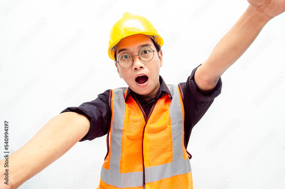 Portrait of a joyful male construction worker or engineer taking selfie and holding camera with hands over white background. asian male engineer open arms for a hug and giving surprise gesture. Portrait of a joyful male construction worker or engineer taking selfie and holding camera with hands over white background. asian male engineer open arms for a hug and giving surprise gesture.