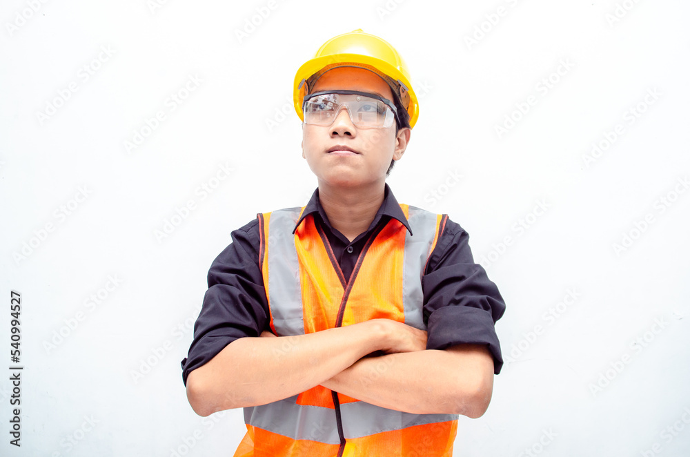 Portrait of a young confident engineer or construction worker in safety yellow helmet and orange vest Portrait of a young confident engineer or construction worker in safety yellow helmet and orange vest