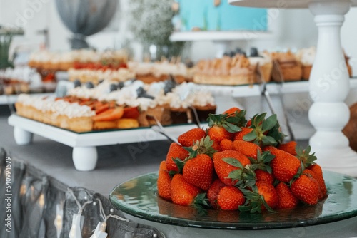 Beautiful shot of a plate full of strawberries on a table with other candies
