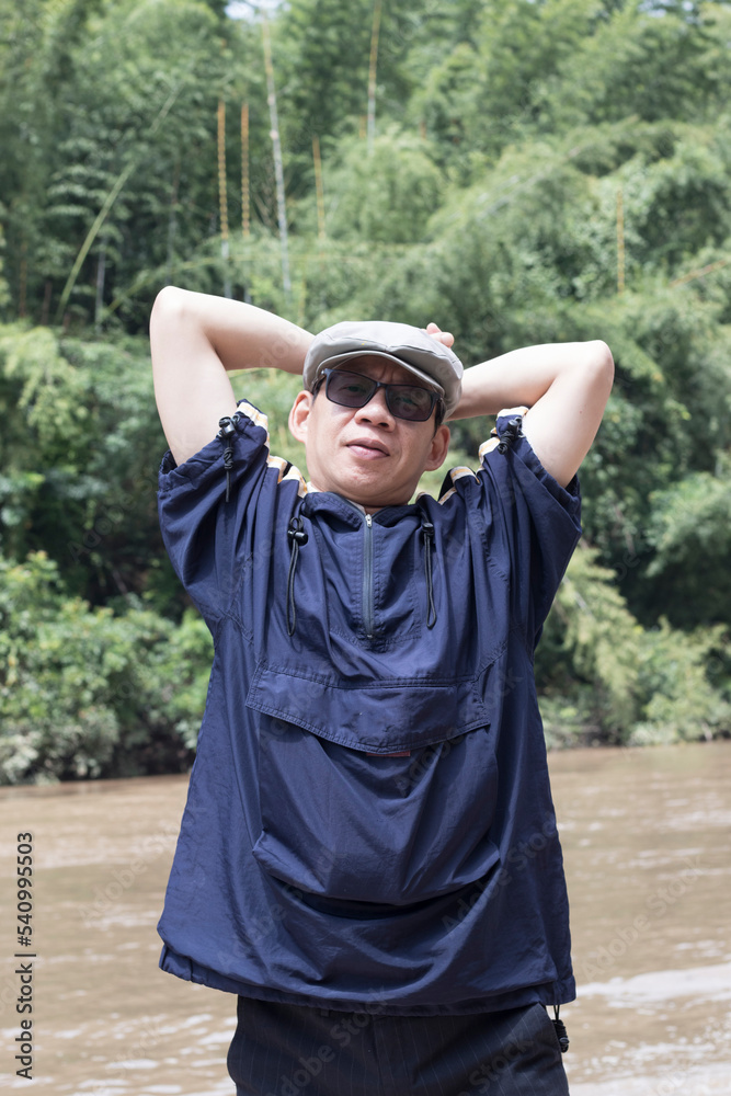 Portrait of an active man wearing a hat and glasses in sportswear by the river his cheerful, fun, relaxed, happy solo travel.