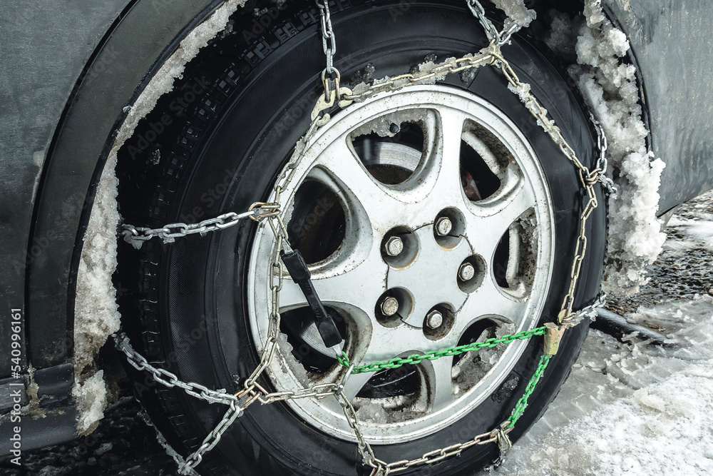 Car wheel with chains. Closeup. Fenders of the car clogged with snow