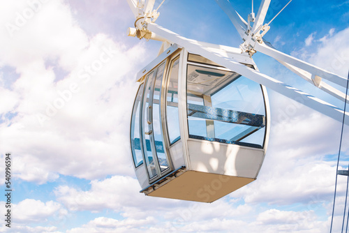 The white cockpit of a refurbished ferris wheel. Empty booths of an amusement attraction.